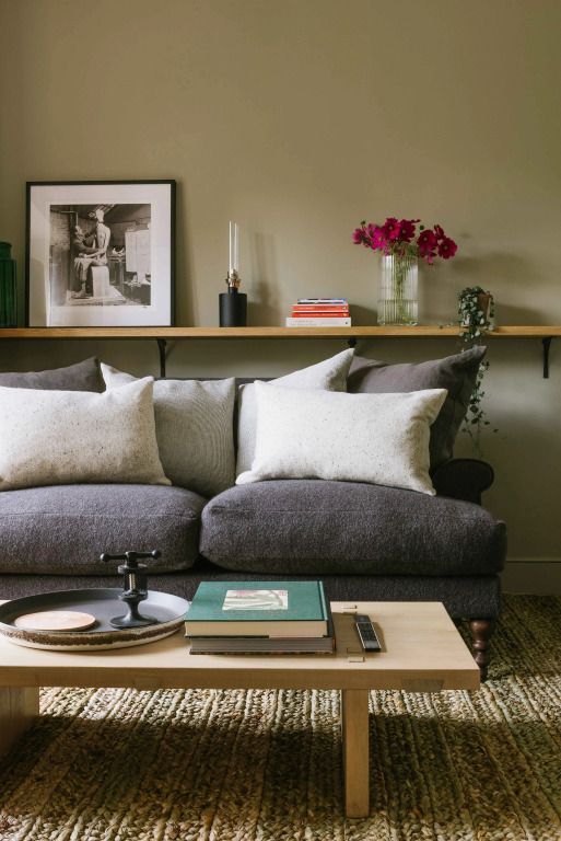 Gemütliches Sofa mit hellen Kissen in einem stilvollen Zimmer mit Blumen und Kunst