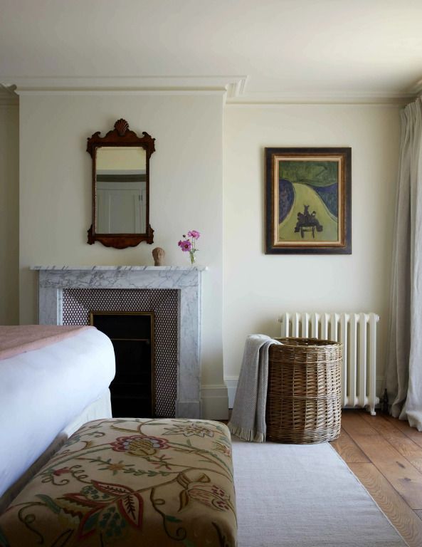 Elegantes Schlafzimmer mit Kamin, Korbgeflecht und Kunstwerken an den Wänden