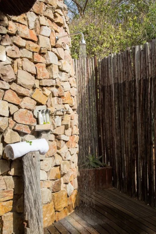 Outdoor-Dusche aus Naturstein umgeben von Holzstämmen beim Hopewell Private Game Reserve.