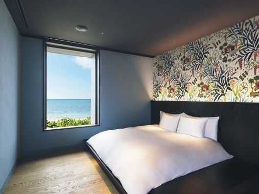 Zimmer mit Doppelbett und Meerblick durch ein großes Fenster