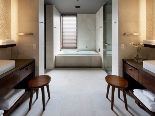 Elegantes Badezimmer mit Badewanne und zwei Holzschemel
