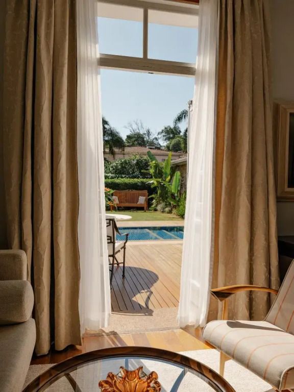 Blick von einem Zimmer auf eine Terrasse mit Pool und Garten im Hintergrund