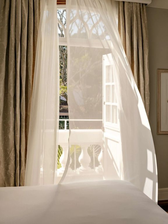 Offenes Fenster mit weichen, fließenden Vorhängen und Blick nach draußen.