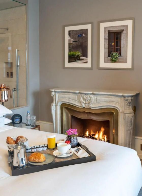 Elegantes Zimmer mit Kamin und Frühstückstablett im Ritz-Carlton Genf.