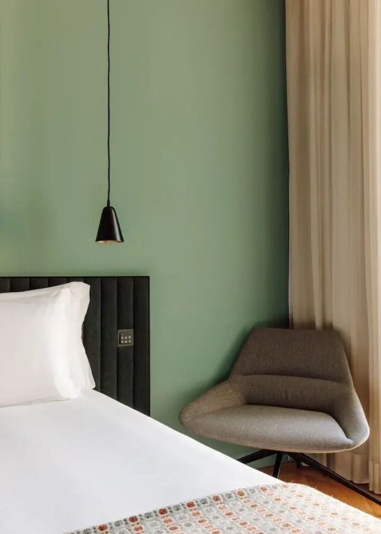 Detailansicht einer gemütlichen Ecke mit Sessel neben dem Bett im Zimmer.