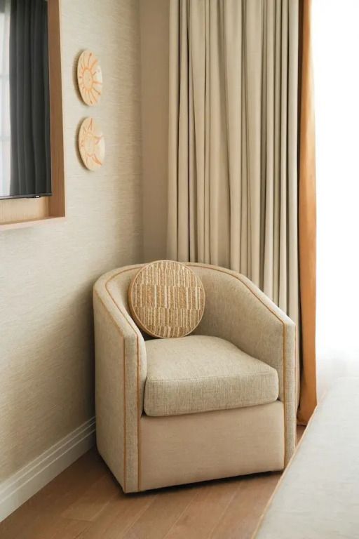 Gemütlicher Sessel in elegantem Zimmer mit hellen Vorhängen und geschmackvollen Details.