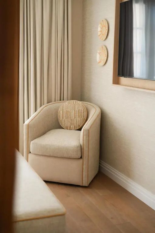 Eleganter Sessel neben Vorhängen in modernem Hotelzimmer mit geschmackvollen Akzenten.