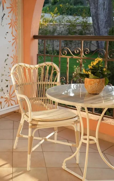 Balkon mit Rattan-Stuhl und Tisch mit Blumendekoration