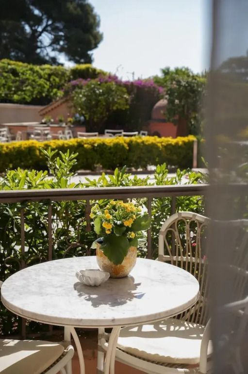 Balkontisch mit Blume im Topf. Hintergrund mit üppigem Garten