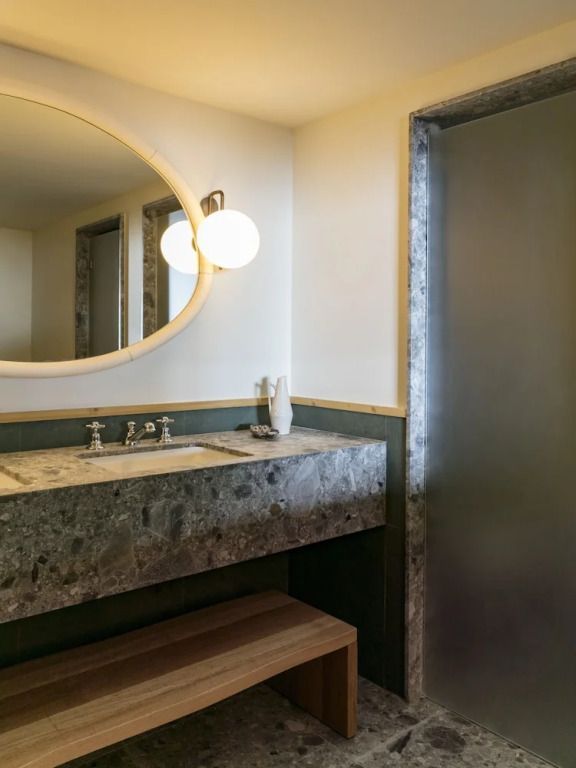 Elegantes Badezimmer mit Natursteinwaschbecken und Rundspiegel