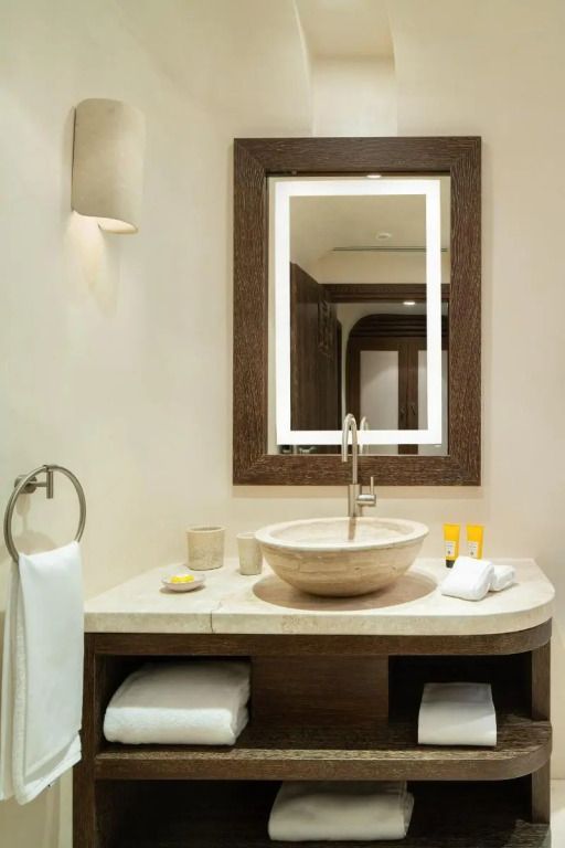 Elegantes Badezimmer mit rundem Waschbecken und großem Spiegel im Hotel Pitrizza