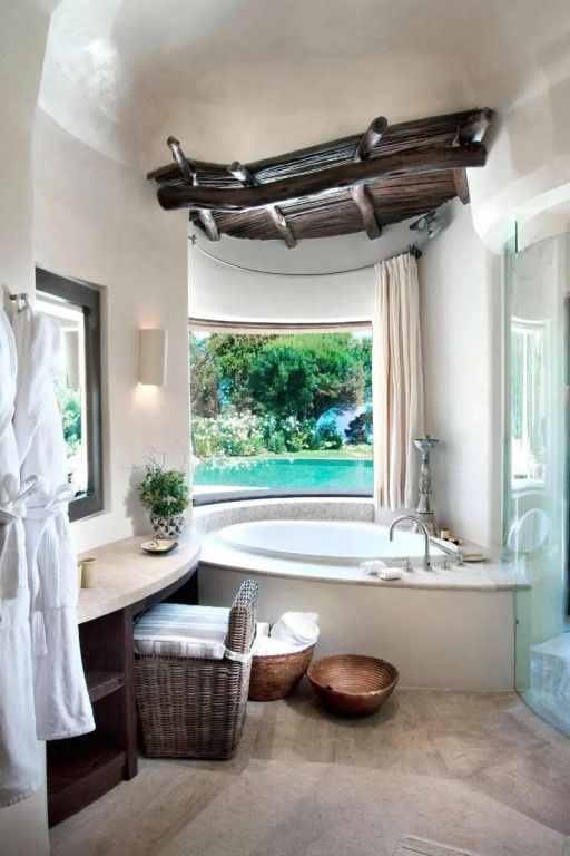 Helles Badezimmer mit runder Badewanne und Blick auf grüne Landschaft im Hotel Pitrizza
