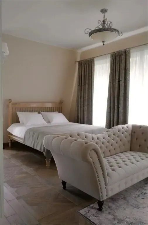 Elegante Avignon Suite mit Doppelbett und luxuriösem Sofa vor bodentiefen Fenstern