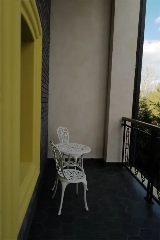 Balkon mit weißen Eisenstühlen und Tisch, Blick ins Grüne