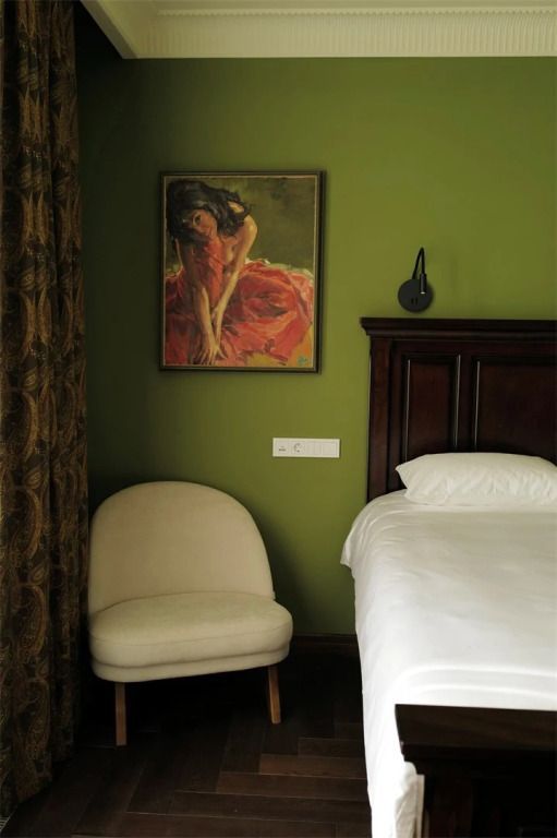 Gemütlicher Bereich im Hotelzimmer mit Kunstwerk an einer grünen Wand