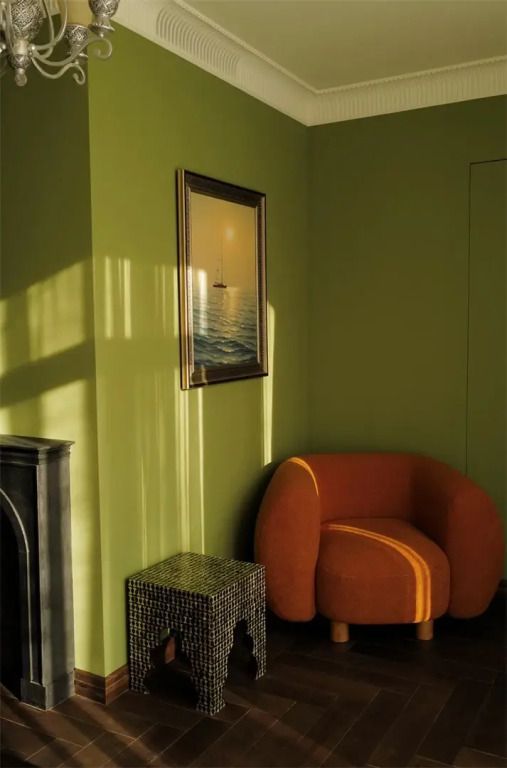 Grünes Hotelzimmer mit orangefarbenem Stuhl und Wandkunst