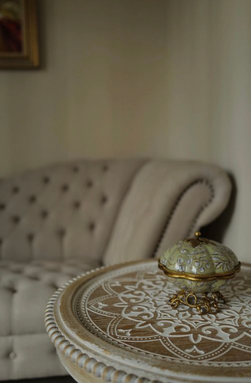 Dekorativer Tisch mit Schmuckdose und Sofa im Hintergrund