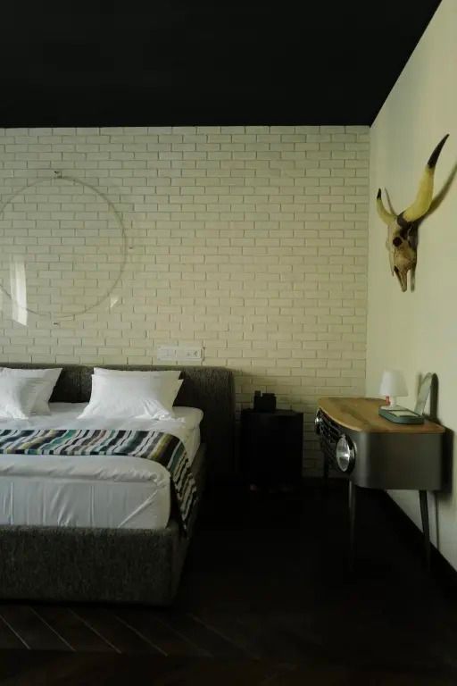 Modernes Schlafzimmer mit Doppelbett und Kopfschmuck an der Ziegelwand