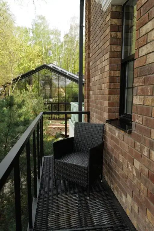 Balkon mit Korbsessel und Blick in den grünen Garten