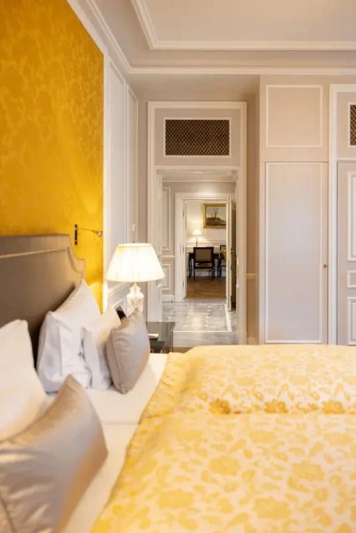 Elegantes Schlafzimmer mit gelber Akzentwand und luxuriöser Bettwäsche