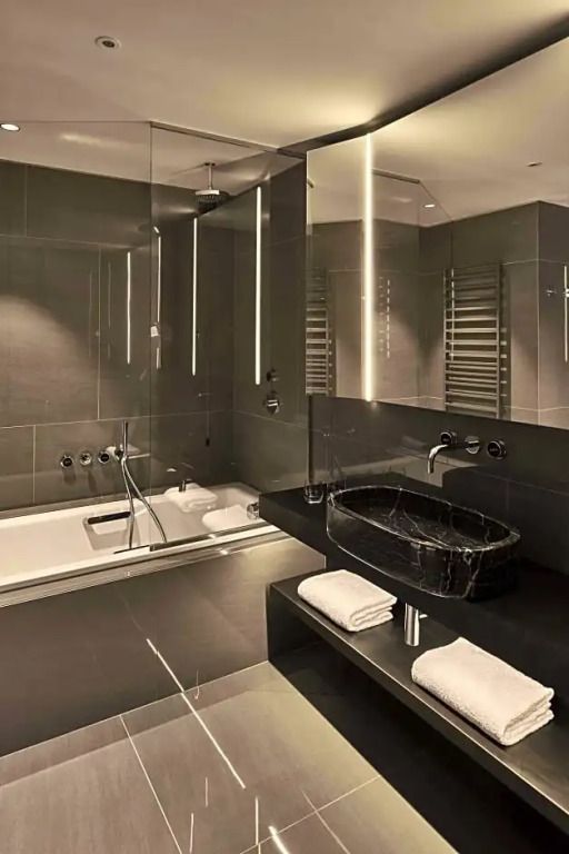 Großes dunkles Badezimmer mit Badewanne und stilvollen Armaturen