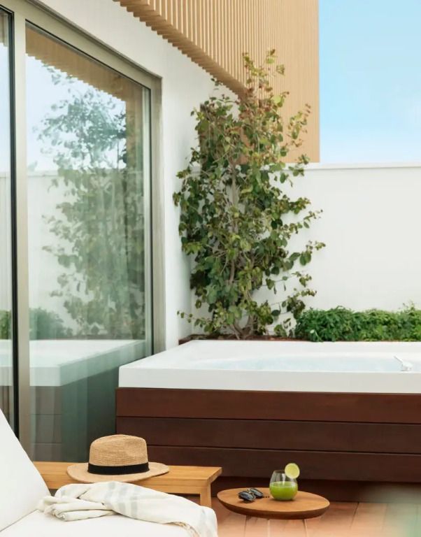 Private Terrasse mit Whirlpool und Sonnenschirm neben Glasschiebetür