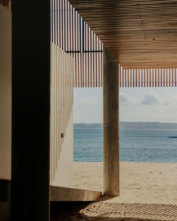 Blick auf den Strand durch moderne Architektur mit direktem Zugang zum Meer.