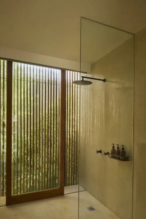 Modernes Badezimmer mit Regendusche und Blick ins Grüne.