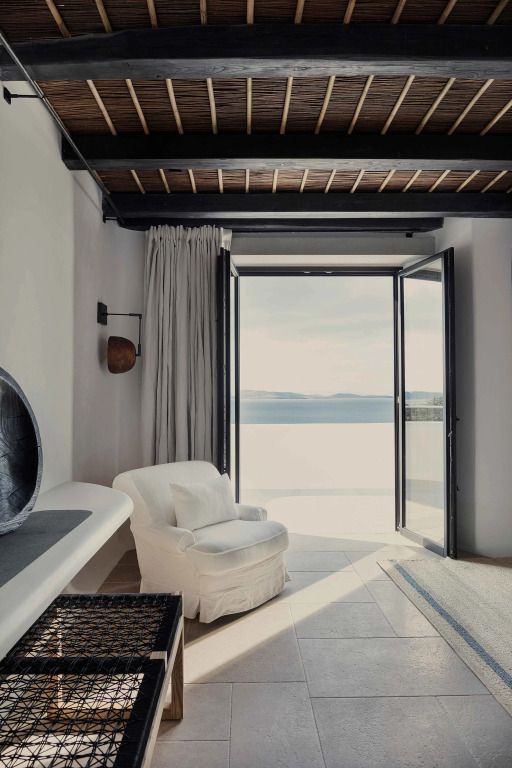 Lounge-Bereich mit Sessel und offenem Fenster mit Meerblick
