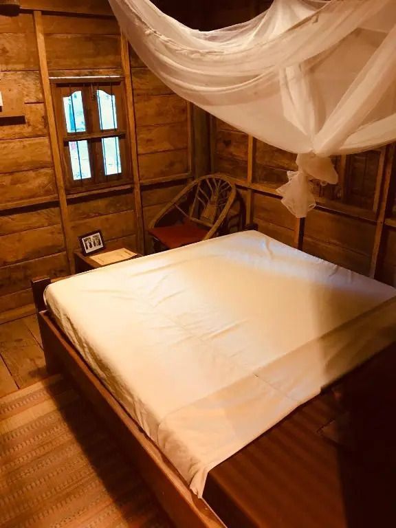 Holzinterieur eines Bungalows mit Bett und Moskitonetz