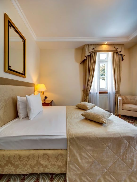 Luxuriöses Schlafzimmer mit Doppelbett und eleganten Vorhängen in der Grand Deluxe Suite