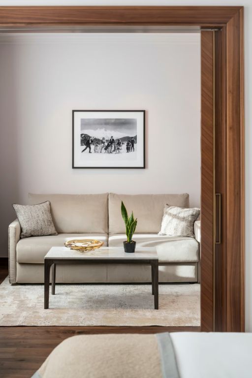 Gemütlicher Wohnbereich mit beiger Couch, Couchtisch und wandhängendem Kunstwerk.