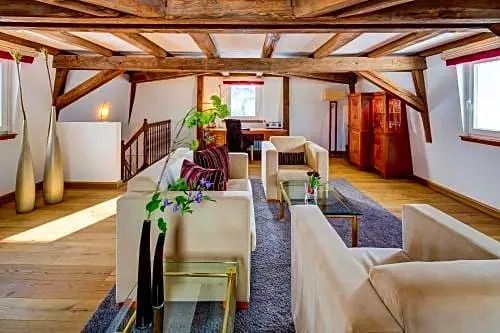 Großzügiger Wohnbereich mit Holzdeckenbalken und bequemen Sitzmöbeln in einer Suite.