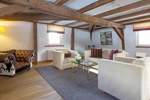 Heller Wohnbereich mit ruhiger Atmosphäre, weißen Sofas und sichtbaren Deckenbalken.