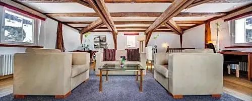 Einladender Sitzbereich in der Suite mit Holzbalkendecke und eleganten Möbeln.