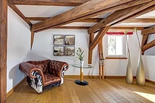 Gemütliche Ecke mit rustikalem Ledersessel und dekorativen Elementen unter Holzbalken.