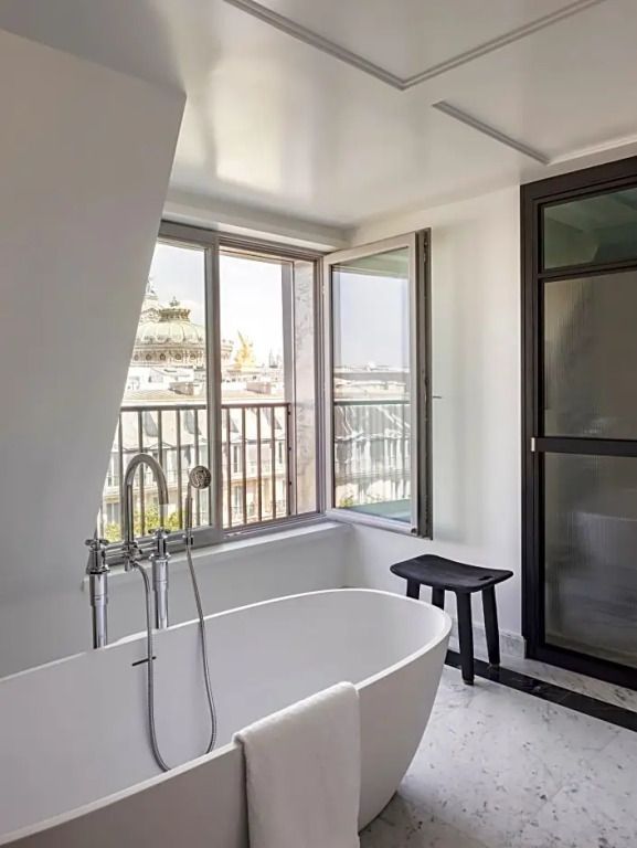 Große Badewanne mit Blick auf die Stadt durch große Fenster.