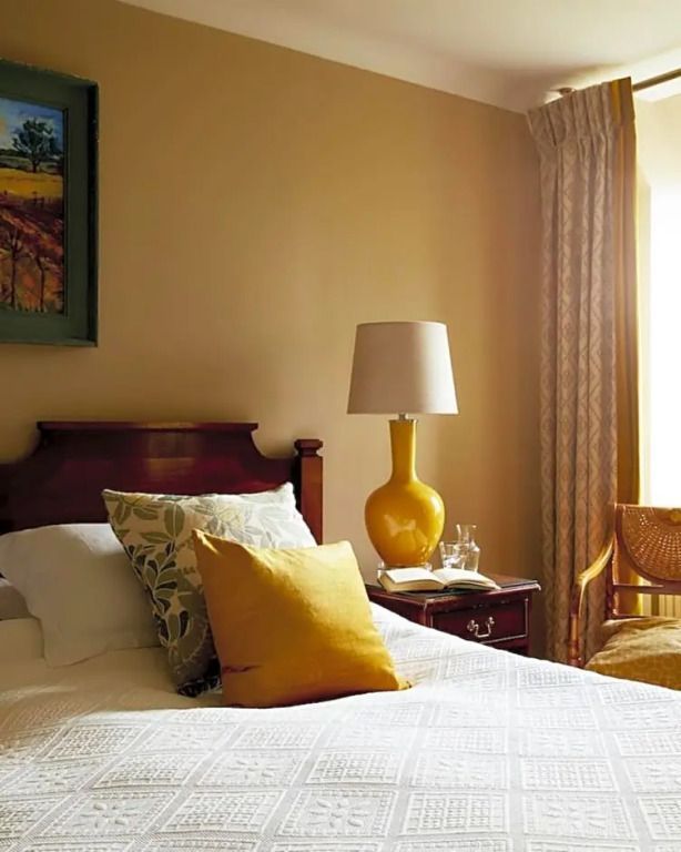 Gemütliches Standardzimmer mit Doppelbett, gelber Lampe und großen Fenster.
