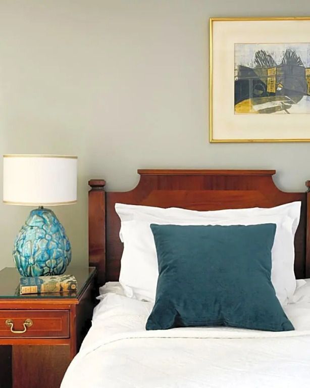 Standardzimmer mit Holz-Doppelbett, blauer Kissen und Kunst an der Wand.