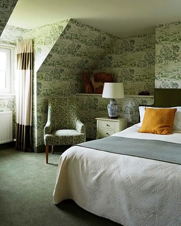 Gemütliche Suite mit Blumenmuster-Tapete und elegantem Sessel.