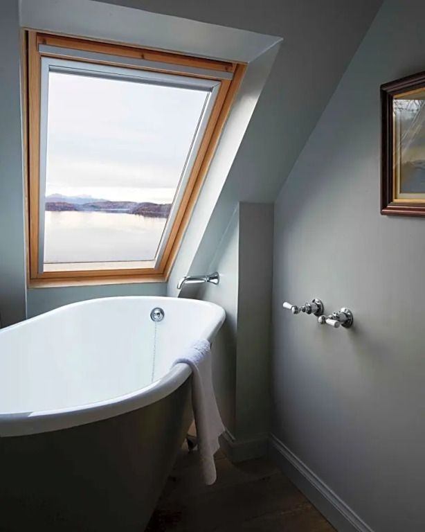 Freistehende Badewanne mit Dachfensterblick auf den See.