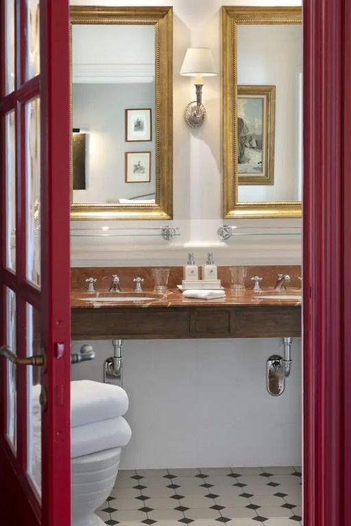 Detail eines Badezimmereingangs mit zwei goldenen Spiegeln und edlen Armaturen