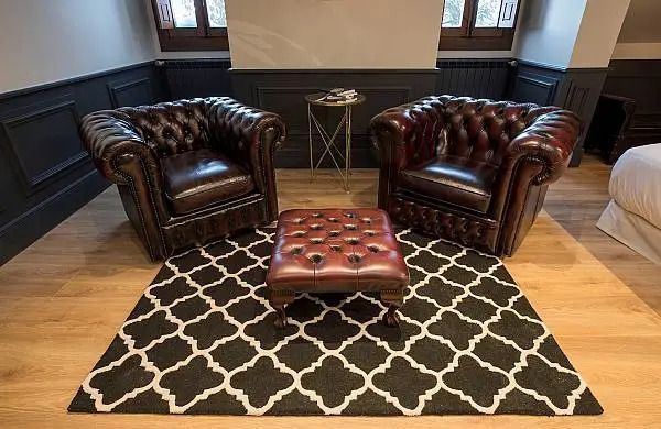 Zwei Ledersessel mit Hocker auf einem stilvollen Teppich