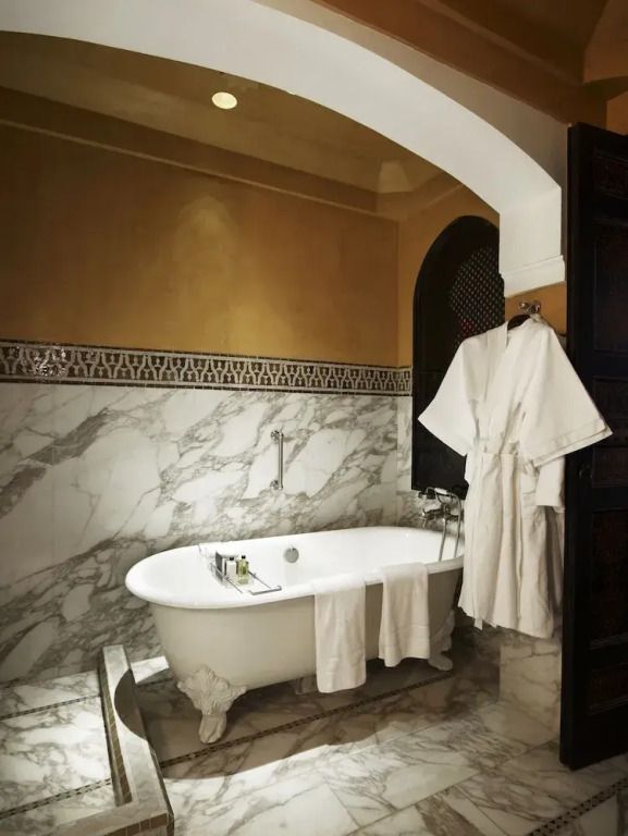 Freistehende Badewanne mit Marmordetails und Bademänteln in der Hivernage Suite