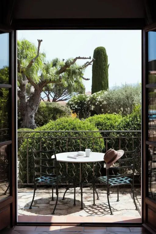 Blick auf eine Terrasse mit Tisch und Stühlen umgeben von gepflegten Gärten.