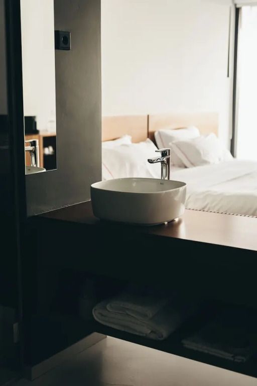 Elegantes Badezimmer mit ovalem Waschbecken und Blick auf großes Bett.
