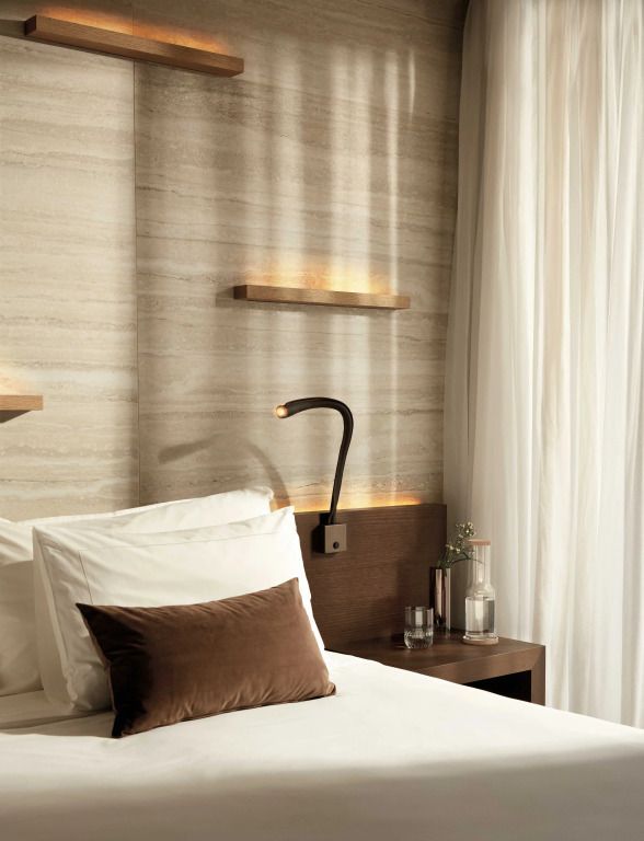 Gemütliches Schlafzimmer mit Bett, Kissen, Holzregalen und Vorhängen im Lefay Resort Dolomiti