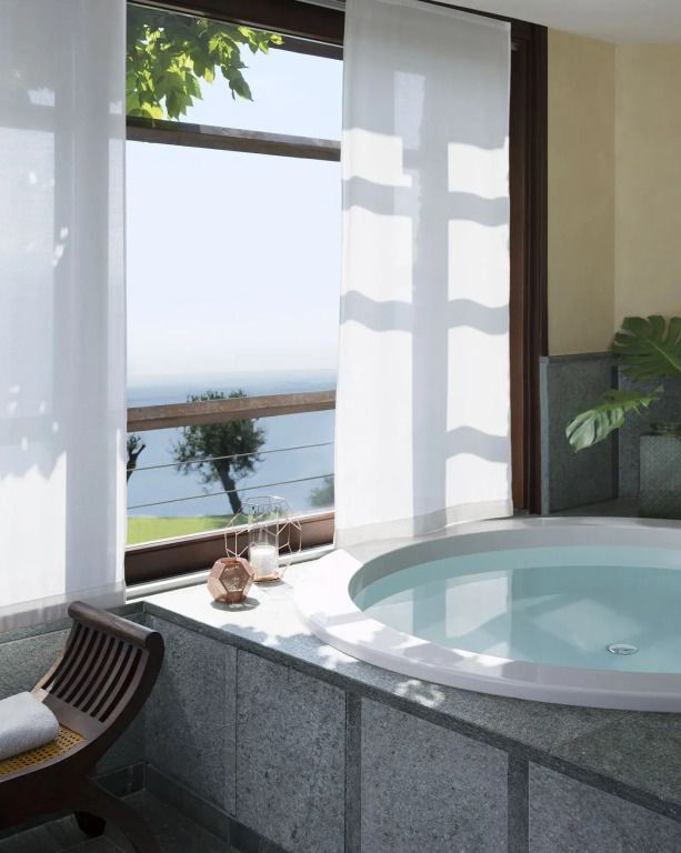 Privater Whirlpool mit Panoramablick auf den See durch große Fenster.