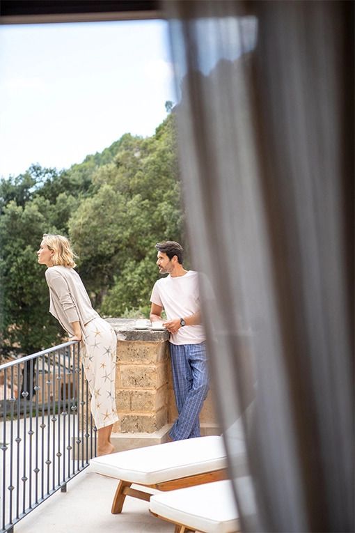 Zwei Personen betrachten die Aussicht von einer Terrasse im Grünen mit Waldlandschaft