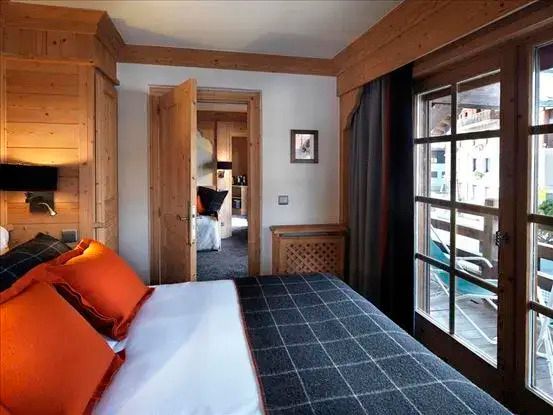 Geräumiges Schlafzimmer mit weißem Bett und orangefarbenen Kissen im Chalet-Stil